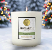 Monarch Candle labeled “Bayberry” glowing gently in a white luxury glass vessel against a warm festive holiday background.