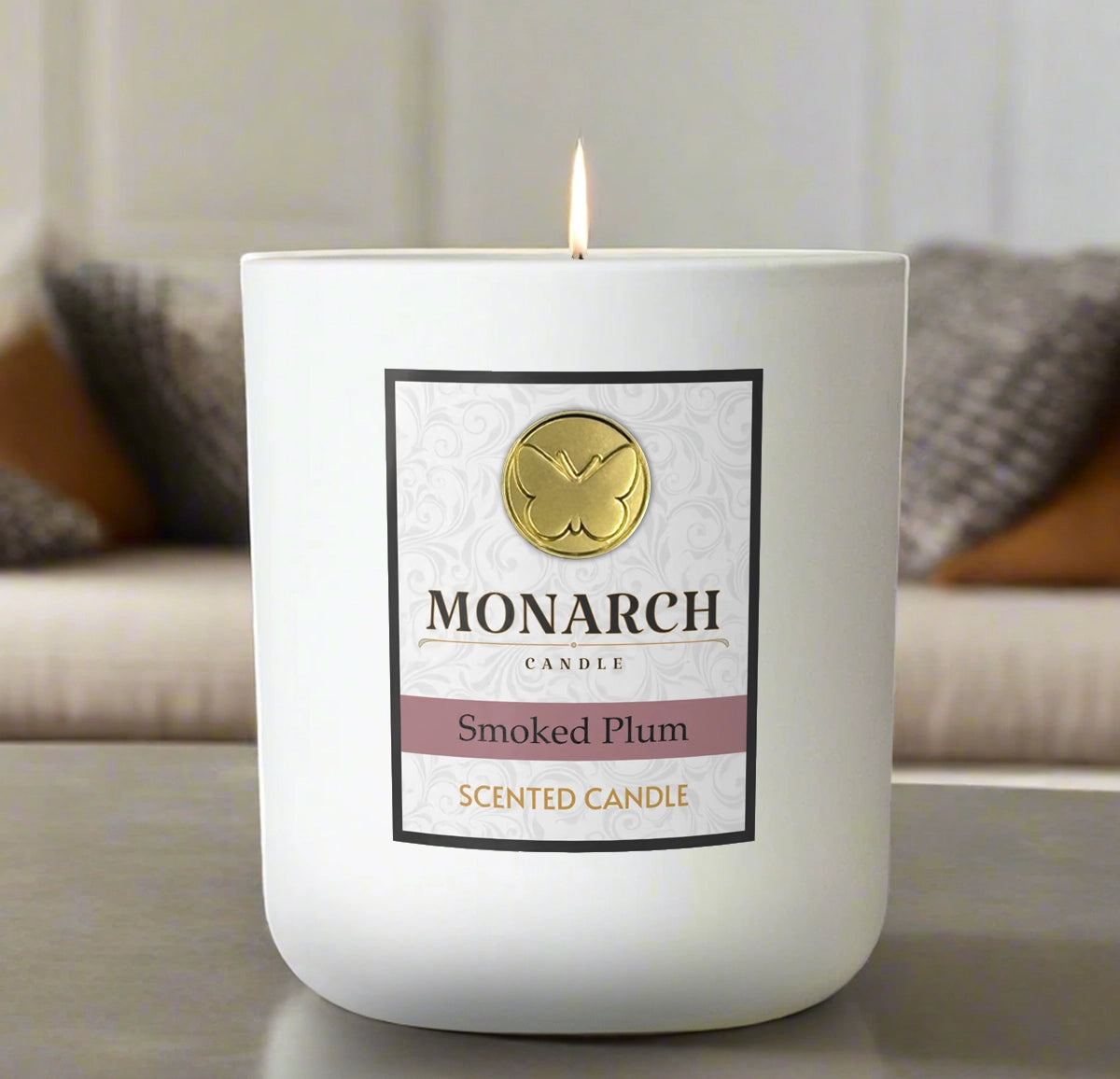 Monarch Candle labeled “Smoked Plum” glowing gently in a white luxury glass vessel against a warm indoor background.