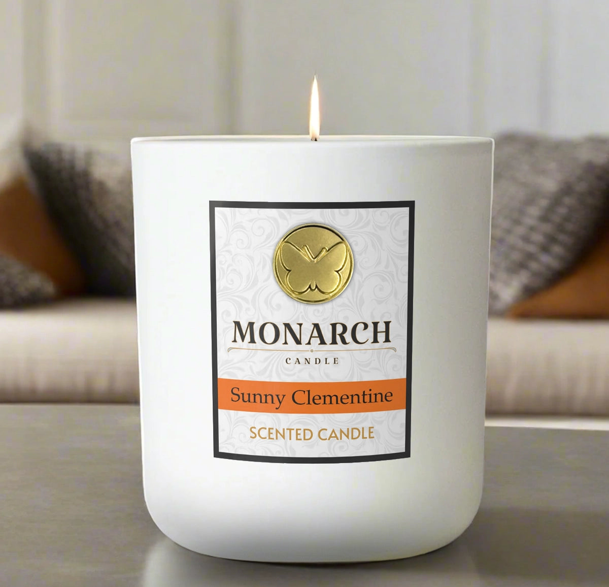 Monarch Candle labeled “Sunny Clementine” glowing gently in a white luxury glass vessel against a warm indoor background.